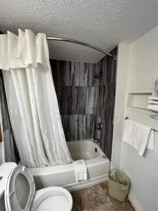 萨斯卡通世福特小屋萨卡囤酒店的浴室设有卫生间和带淋浴帘的浴缸。