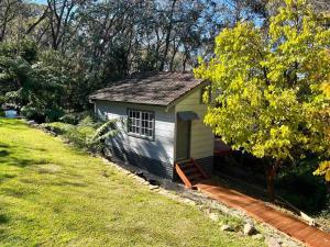 卢拉Bottlebrush Cabin, cosy private cabin in the trees的田野旁院子中的一个小棚子