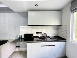 古尔冈BedChambers Luxurious Serviced Apartment in Gurgaon的厨房配有白色橱柜和黑色台面