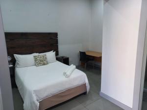 比勒陀利亚Triple9 Hatfield Guesthouse的卧室配有白色的床和木制床头板