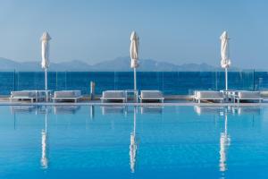 Ágios FokásDimitra Beach Hotel & Suites的一个带椅子和水的游泳池