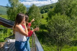 什切尔克Apartamenty Pod Gondolą - Mountain Resort Villa z sauną - Dream Apart的两个女孩站在阳台上,一边喝杯酒