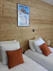 Villars-Colmars马塔贡餐厅酒店的卧室设有两张床铺,卧室设有木墙,墙上挂着一幅画