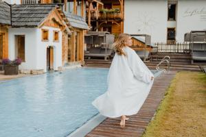 恩斯塔尔豪斯霍夫莱纳健康大自然酒店的身着白色衣服的女人站在游泳池旁