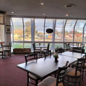旺加拉塔旺加拉塔汽车旅馆 的餐厅设有桌椅和大窗户。