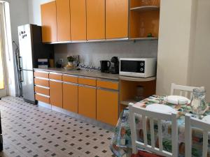 都灵Casa di Max by Holiday World的厨房配有橙色橱柜、桌子和微波炉