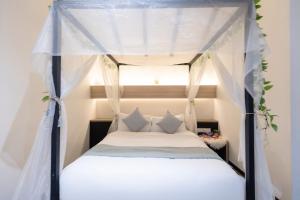 新加坡Hotel NuVe的卧室配有带白色床单和枕头的天蓬床。