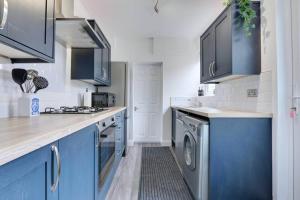 克利索普斯Cosy home by the sea的厨房配有蓝色橱柜、洗衣机和烘干机
