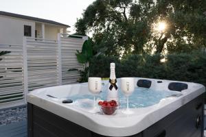 帕奇斯Pachis Escape Suites的热水浴池,配有一瓶葡萄酒和玻璃杯