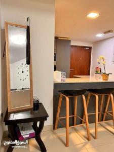 马斯喀特One Bed Room Apartment Muscat Hills的厨房配有带镜子的柜台和2把凳子
