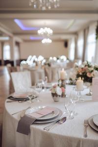 可罗日采Hotel Hetman的一张桌子,上面有白色的桌布,盘子和银器