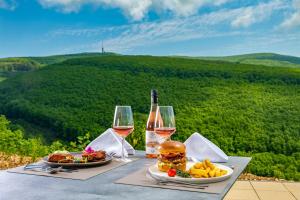 玛特阿哈泽Hotel Ózon & Luxury Villas的一张桌子,上面放着两杯葡萄酒和汉堡包