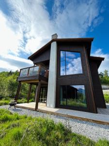 斯特兰达Premium Penthouse near Strandafjellet Ski Resort & Geiranger - Panoramic Mountain Views & Sauna的一面设有玻璃窗的房子