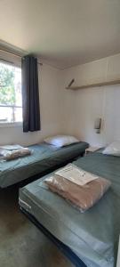 阿格德Camping Parc des 7 Fonts的两张床位于带窗户的房间内