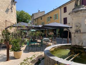 Saint-Michel-lʼObservatoireHôtel Restaurant L’Observatoire的庭院里的喷泉,配有桌子和遮阳伞