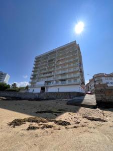 阿罗萨新镇Apartamento Arousa Mar的海滩上的一座建筑,阳光在天空中