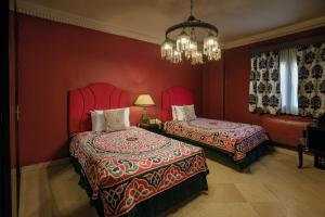 开罗Le Riad Hotel de Charme的红色卧室设有两张床和吊灯。
