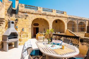 MunxarMatli Farmhouse, your stunning Gozo getaway.的天井配有桌椅和比萨饼烤箱