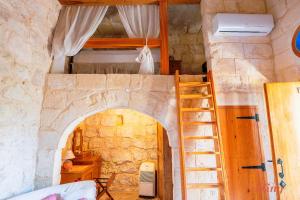 MunxarMatli Farmhouse, your stunning Gozo getaway.的一间设有楼梯的客房,通往石墙