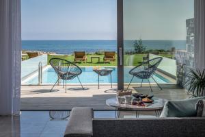 古瓦伊Crete Resort Sea Side Suites "Adults Only" by Checkin的一个带两把椅子和一张桌子的庭院和一个游泳池