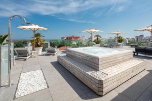利尼亚诺萨比亚多罗Hotel Monaco的一个带热水浴缸、椅子和遮阳伞的庭院