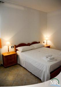 阿尔盖罗Residence Hotel Monte Ricciu的一间卧室配有一张大床,桌子上放着两盏灯