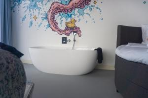 艾默伊登劳乌安娜德卡德酒店的浴缸位于波浪壁画的房间