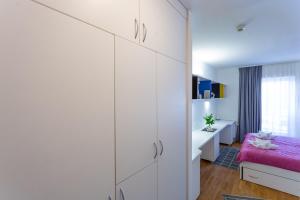 斯普利特Rooms Kampus的卧室配有白色橱柜和粉红色的床。