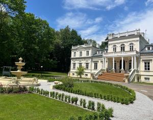 Wola ChojnataPałac Chojnata的一座大型的白色豪宅,庭院里设有一个喷泉