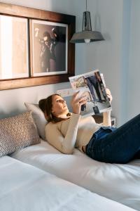 特鲁埃尔Apartamentos One的躺在床上看杂志的女人