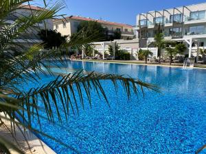 帕拉利米尼Mythical Sands Resort - Good Vibes Apartment的一座大型蓝色游泳池,位于大楼旁边