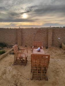 锡瓦Friendo's House & Hot Spring的墙上的沙子里有三把椅子和一张桌子