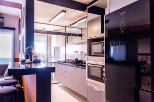 索罗卡巴Loft Campolim的厨房配有白色橱柜和黑色台面