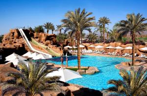 沙姆沙伊赫Sentido Reef Oasis Aqua Park Resort的一个带棕榈树和滑梯的游泳池的度假酒店