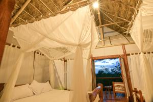 卡塞斯Kazinga Wilderness Safari Camp的一间卧室配有一张天蓬床和窗户