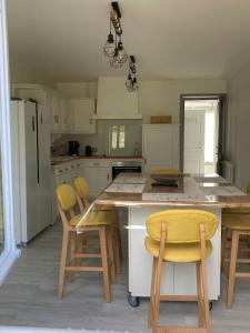 FeingsGITE DE LA CAZELLERIE的厨房设有黄色椅子的大岛