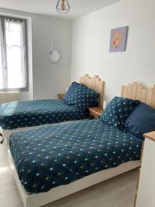 FeingsGITE DE LA CAZELLERIE的一间卧室设有两张带蓝色床单的床和窗户。