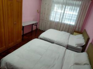 诗巫Sibu kulas homestay的客房设有两张床、一张桌子和一个窗户。