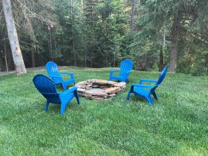 CoramGlacier Homestead的三个蓝色椅子坐在草地上的火坑周围