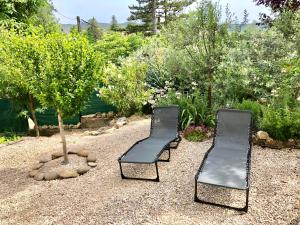 格雷乌莱班La rocaille du château的花园里有两把黑色椅子,有树