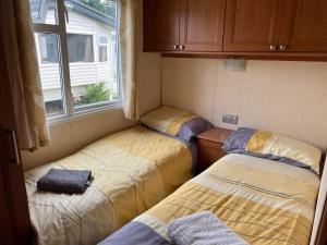 亨斯坦顿Heacham Golden Sunset Caravan Pets go Free的一间小房间设有三张床,设有窗户