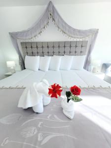 奥科苏尤Amantani palace的一间卧室配有一张带毛巾和两朵玫瑰的床