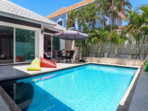 南芭堤雅CityHouse-OSCAR,pool villa 4Bedrooms-Jacuzzi-walking Street 10min的一座房子旁带遮阳伞的游泳池