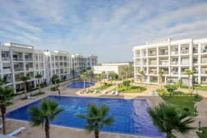 布兹尼盖Bouznika plage costa的公寓大楼设有游泳池和棕榈树