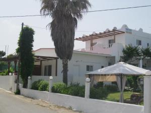 吉奥塔略克拉尼亚海边一室公寓酒店的一座白色的房子,上面有棕榈树和遮阳伞
