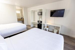 萨凡纳Oneway Savannah的酒店客房设有两张床、一张书桌和电视