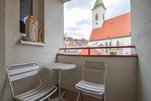 布拉迪斯拉发Apartment Old Centre - Panska的一个带两把椅子和一张桌子的阳台和一个教堂
