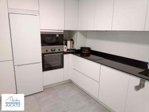 蒙达卡APARTAMENTO AKATZ的白色的厨房配有白色橱柜和电器