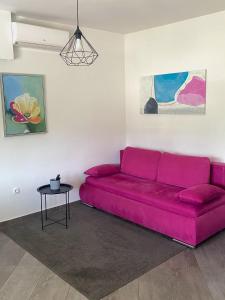 里耶卡Tijara Apartment的客厅配有一张粉红色的沙发,配有一张桌子