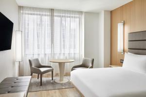 休斯顿AC Hotel by Marriott Houston Downtown的酒店客房带一张床、一张桌子和椅子